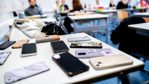 Eingesammelte Smartphones in einer Schulklasse. Ab Februar nächsten Jahres soll es in RLP ein Verbot der privaten Nutzung von Handys bis zur Klasse 10 geben.