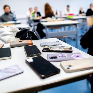 Eingesammelte Smartphones in einer Schulklasse. Ab Februar nächsten Jahres soll es in RLP ein Verbot der privaten Nutzung von Handys bis zur Klasse 10 geben.