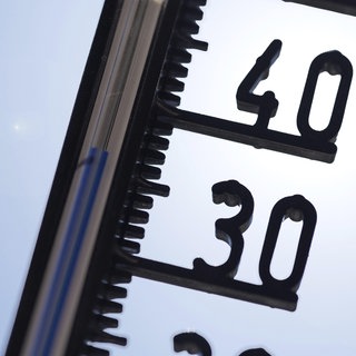 Symbolbild Hitze: Thermometer vor wolkenlosem Himmel.
