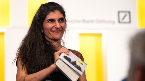 Die Gewinnerin des Deutschen Buchpreises 2026, Shida Bazyar, steht auf der Bühne.