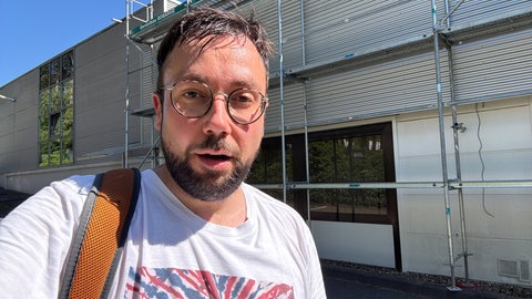 SWR-Reporter Johannes Zinßmeister kommt nass geschwitzt von einem Dach im Industriegebiet Kaiserslautern.