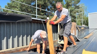 Die Dachdecker Rolf und Evald arbeiten bei mehr als 30 Grad und praller Sonne auf einem Dach in Kaiserslautern.