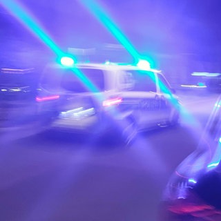 In Kaiserslautern eskalierte am Wochenende ein Streit, sodass ein 27-Jähriger mit einem Messer verletzt wurde. Ein Polizeiauto fährt mit Blaulicht durch die Nacht.