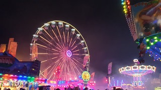 Blick auf das Riesenrad und bunte Lichter im Dunkeln auf der Oktoberkerwe in Kaiserslautern.