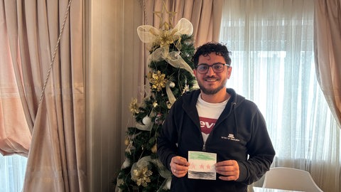 Suliman Belal aus dem Donnersbergkreis mit einem gemalten Bild der syrischen Flagge von seinem Kind. 