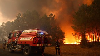Feuerwehrleute versuchen in der Nähe von Le Porge im Südwesten Frankreichs mit einem Waldbrandlöschfahrzeug, die brennenden Bäume zu löschen.