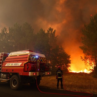 Feuerwehrleute versuchen in der Nähe von Le Porge im Südwesten Frankreichs mit einem Waldbrandlöschfahrzeug, die brennenden Bäume zu löschen.