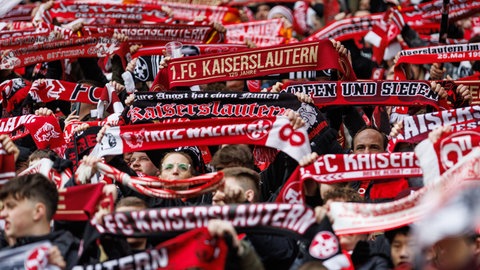 FCK-Fans halten FCK-Schals hoch und feuern ihr Team an.