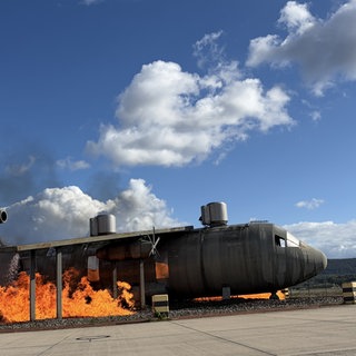 Training on the job: An der Brandsimulationsanlage (Aircraft Fire Training Mockup) wird ein Flugzeug wie die Lockheed C-130 Hercules in Brand gesetzt. 