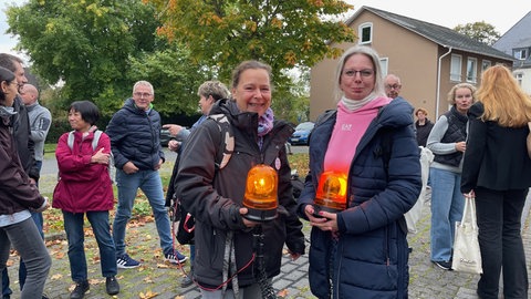 Mehrere Teilnehmer stehen bei einer Mahnwache mit Leuchtsignalen vor dem Kreistag in Altenkirchen