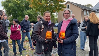 Mehrere Teilnehmer stehen bei einer Mahnwache mit Leuchtsignalen vor dem Kreistag in Altenkirchen