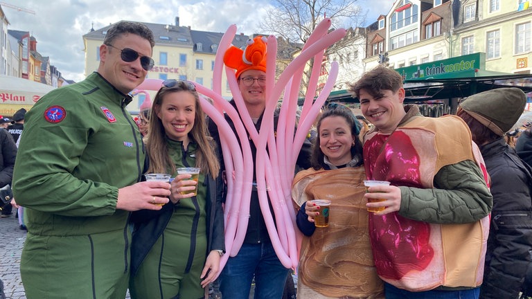 Am Schwerdonnerstag 2025 wird in der Koblenzer Innenstadt ausgelassen gefeiert - so wie diese vier jungen Leute in ihren bunten Kostümen. 
