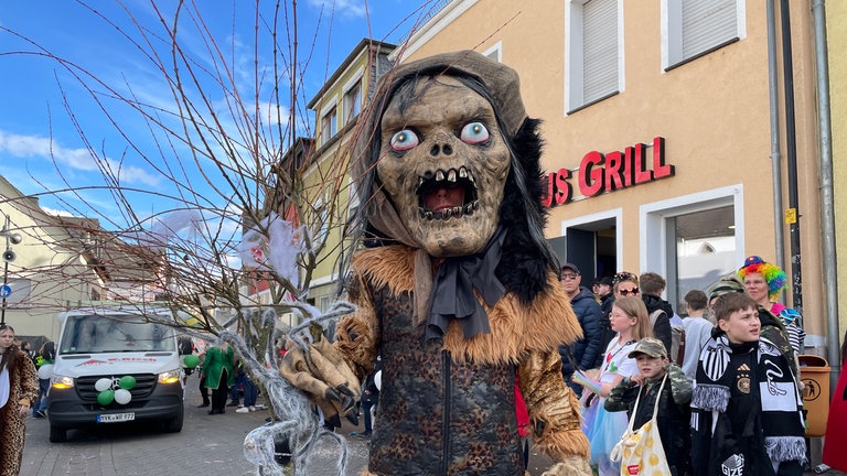 Beim Möhnenumzug in Mülheim-Kärlich hat sich ein Mann als riesiges Monster verkleidet.