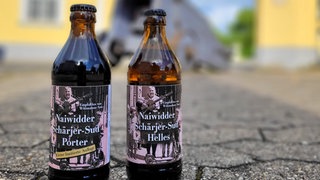 Zwei Flaschen des "Naiwidder Schärjer-Suds" vor der Kulisse des Neuwieder Schlosses