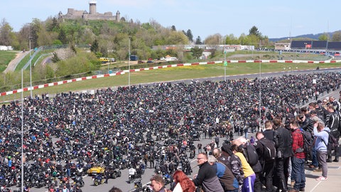 Viele tausend Menschen stehen auf der Rennstrecke Nürburgring. Im Hintergrund die Ruine der Nürburg