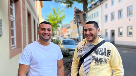 Mohammad Hazaa und Khalil Doubal stehen lachend auf einer Straße in ihrer Heimatstadt Neuwied