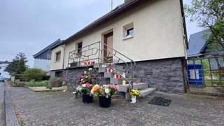 Vor dem Haus der getöteten Familie in Weitefeld haben Menschen Blumen und Kerzen aufgestellt - in Gedenken an das getötete Ehepaar und den erschossenen Jugendlichen.