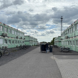 Rechts und links auf dem Bild sieht man aufeinandergestapelte Container, in denen die Schülerinnen und Schüler des Are-Gymnasiums unterrichtet werden.