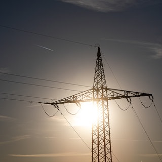 Ein Strommast wird von der Sonne angestrahlt. Verursachen hohe Temperaturen Stromausfälle?