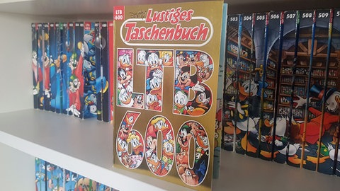 Der 600. Band des Lustigen Taschenbuchs steht in einem Regal
