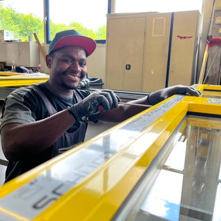 Metallbauer-Azubi Denys Ntegerejumukiza aus Ruanda arbeitet an einer Tür in der Fertigung bei der Firma Reko in Dörth.