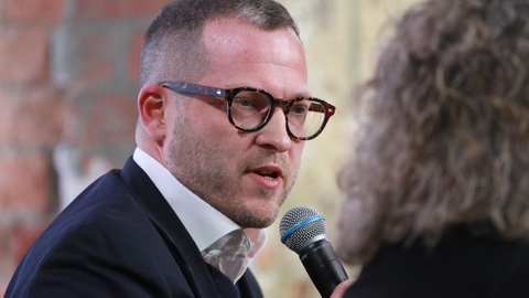 Julian Reichelt, Chefredakteur von Nius, mit einem Mikro in der Hand