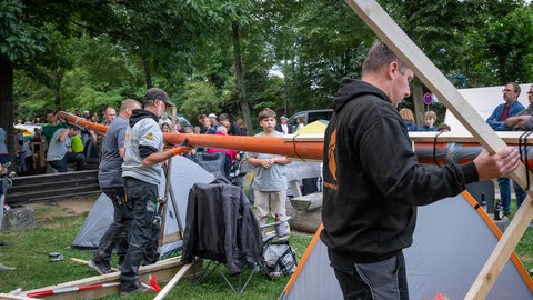 Väter bauen an einer Kugelbahn aus Rohren und Holzkonstruktionen in Mertloch