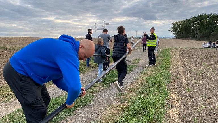 Weltrekordversuch in Mertloch: Ein Mann steckt zwei Kunststoffrohre zusammen für die Kugelbahn