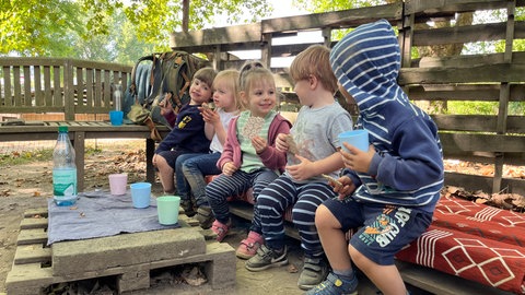 Kinder der Inklusiven Kita Unkel essen einen Snack bei den Ziegen