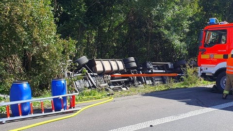 Ein Lkw liegt in einem Grünstück neben der A3. Ein Feuerwehrwagen steht daneben