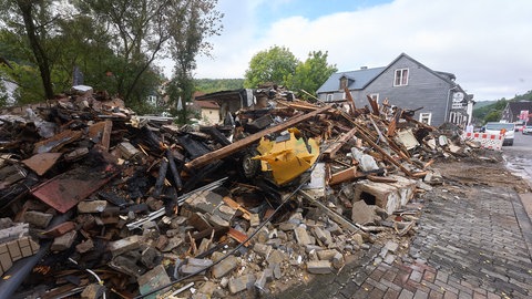 Ein Schuttberg nach der Explosion eines Wohn- und Geschäftshauses in Daaden: Jetzt müssen wegen der Überflutungsgefahr die Trümmerteile beseitigt werden, die in einem nahen Bach gelandet waren. 