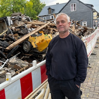 Dirk Kosbab steht vor den Überresten eines Hauses in Daaden. Nach dessen Explosion hatte er einen Jugendlichen aus den Trümmern geholt.