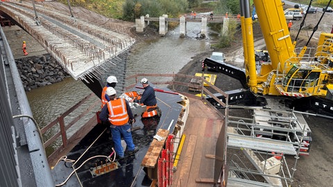 Die Arbeiter prüfen den Einhub der Brücke.