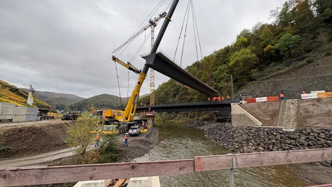 Ein etwa 30 Meter langes Brückenteil wird von einem Schwerlastkran an seine Position gesetzt.