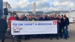Mitarbeiter von ZF in Bad Neuenahr-Ahrweiler bangen um ihren Arbeitsplatz und halten gemeinsam ein Protestbanner hoch.