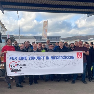 Mitarbeiter von ZF in Bad Neuenahr-Ahrweiler bangen um ihren Arbeitsplatz und halten gemeinsam ein Protestbanner hoch.