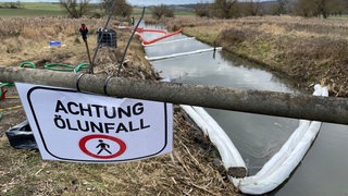 Ein Schild mit der Aufschrift "Achtung Öl-Unfall" hängt an einer Brücke im Naturschutzgebiet Thürer Wiesen.