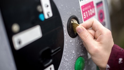 Eine Frau wirft 50 Cent in einen Parkautomaten. In Bad Ems gibt es Streit ums Langzeit-Parken.