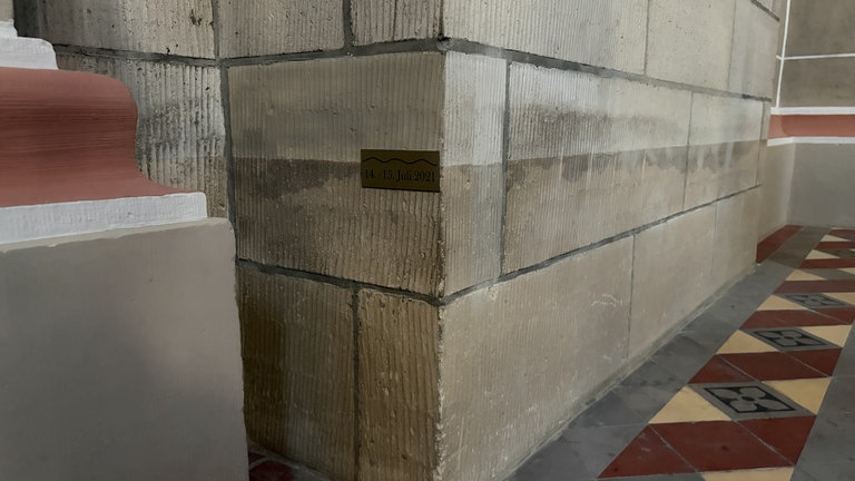 In der Rosenkranzkirche erinnert eine Plakette an der Wand daran, wie hoch das Wasser hier bei der Flut 2021 stand.