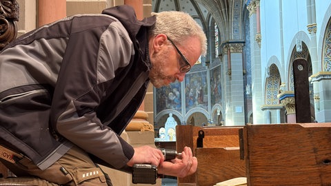 Schreiner Michael Frömbgen zieht die letzten Schrauben an einer eigens angefertigten Kirchenbank an.