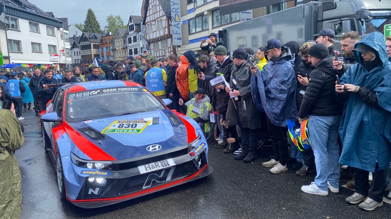 Beim "Racing Day" in Adenau machen Motorsport-Fans Fotos von einem Rennwagen.