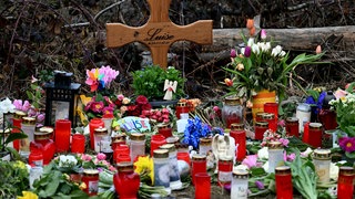 Ein Holzkreuz, Blumen, Kuscheltiere und Kerzen liegen da am Tatort, wo die zwölf Jahre alte Luise aus Freudenberg gestorben ist. Ihre Familie fordert vor dem Landgericht Koblenz Schadenersatz und Schmerzensgeld.