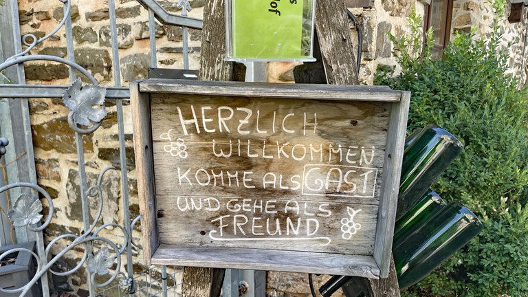 Ein Schild vor einem Haus in Bremm an der Mosel mit der Aufschrift "Komme als Gast und gehe als Freund".