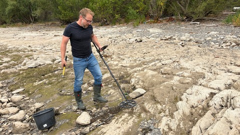 Schatzsucher Christian Ganser ist bei Niedrigwasser mit seinem Metalldetektor am Rheinufer unterwegs