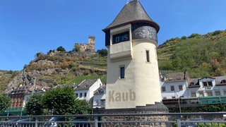 Der Pegelturm in Kaub und dahinter die Stadt Kaub am Rhein.