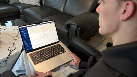 Tom Groß sitzt auf einem Sessel mit einem Laptop auf dem Schoß.