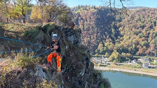 Kletterer lösen Steine am Loreleyfelsen, um ihn zu sichern.