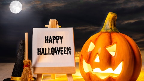 Ein beleuchteter Halloween-Kürbis und ein Schild mit der Aufschrift "Happy Halloween".