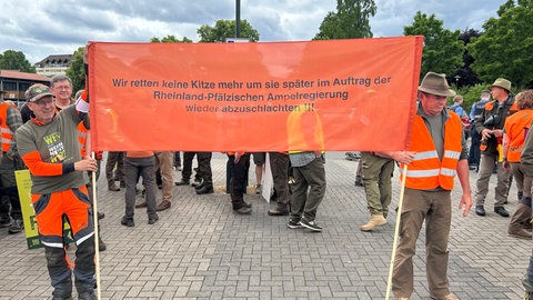Jäger demonstrieren in Bad Dürkheim gegen das geplante Landesjagdgesetz und halten ein Transparent in die Höhe