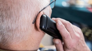Telefonbetrug durch Schockanrufe. Senior hält Telefon. Mann wird in Handschellen abgeführt. 